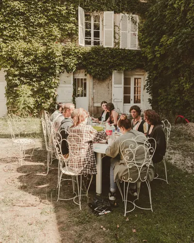 Repas entre invités dans une cour couverte de lierre